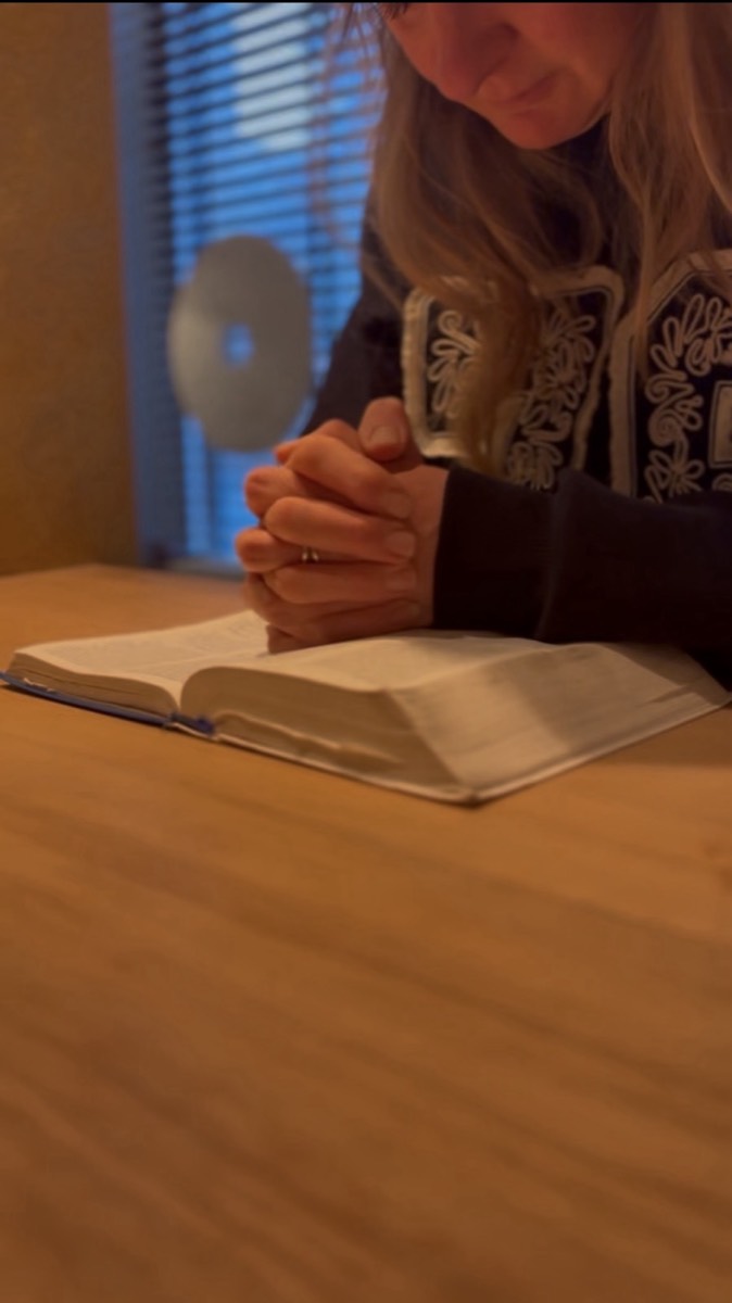 Judith Dijkstra in gebed bij de bijbel